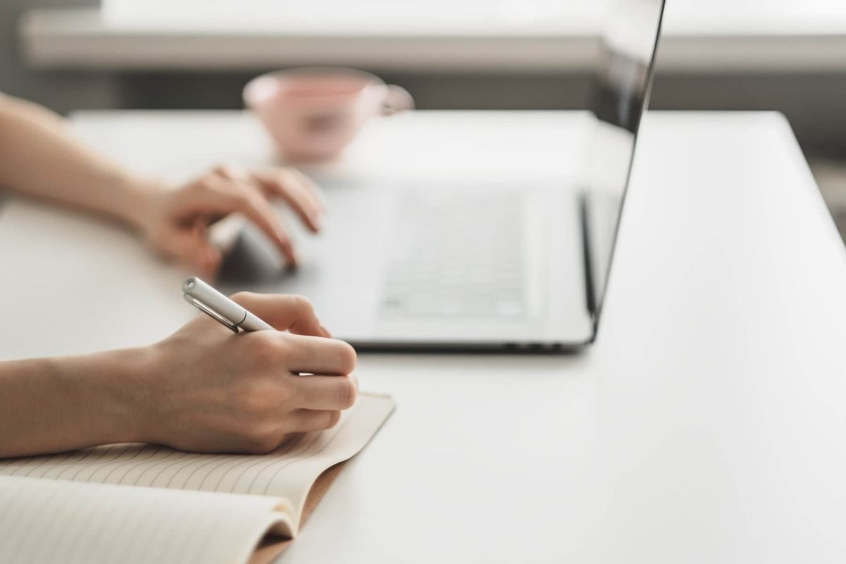 young woman works laptop takes notes notebook scaled